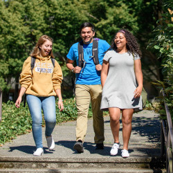 Three students walking and laughing with each other on a sunny day