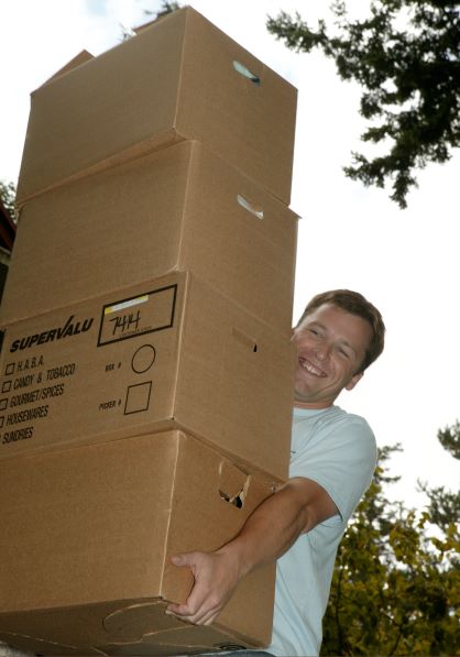 student carrying four stacked boxes on move in day