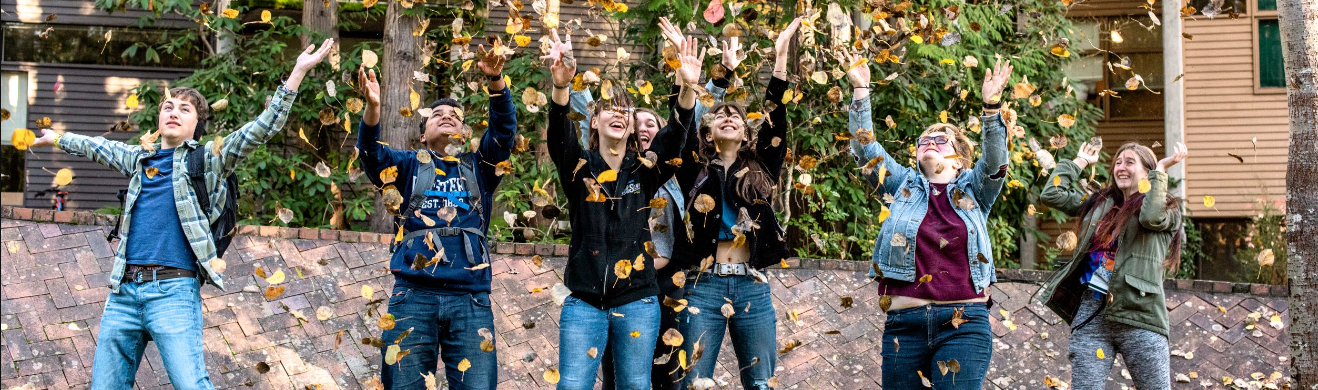 Students tossing leaves up into the air