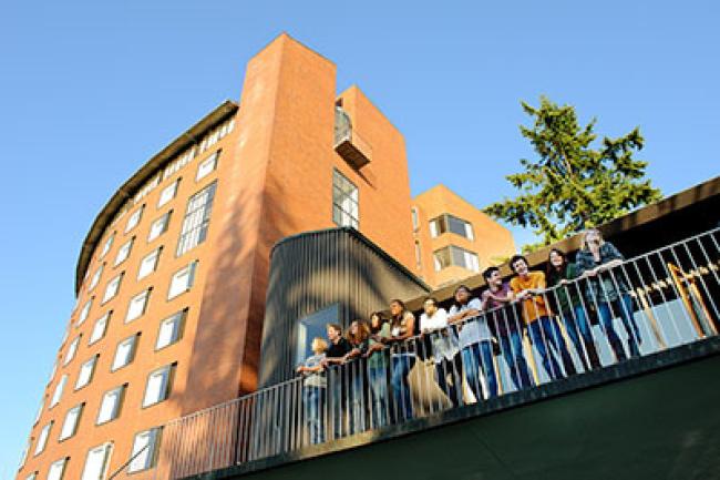 Students on the Mathes hall balcony lean against the railing and look out towards Bellingham Bay