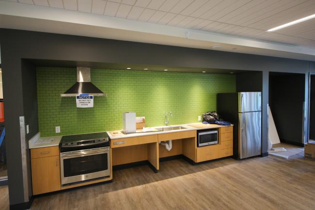Bright kitchen area with green backsplash, stovetop, fridge, and counter space