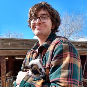 Aiden smiling with baby goat in his arms