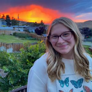 Brianna smiles at the camera with a sunset backdrop