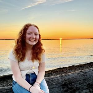 Kaitlyn smiling with a backdrop of the ocean at sunset
